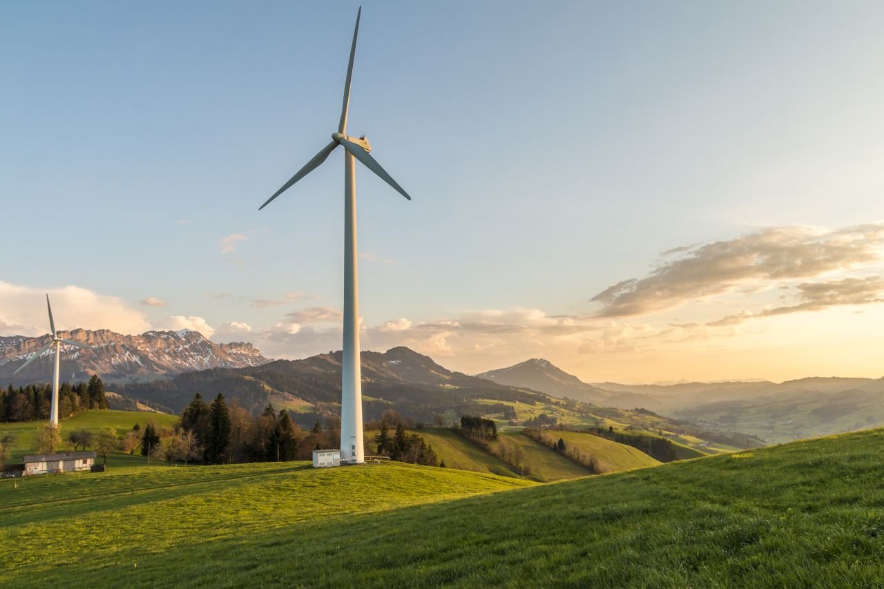 cta-image Peaceful countryside with wind turbines during sunset, showcasing sustainable energy.
